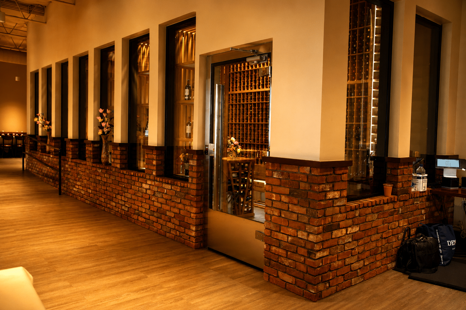 Restaurant wine room entrance and tall glass windows above brickwork, with wooden bottle racks visible inside.
